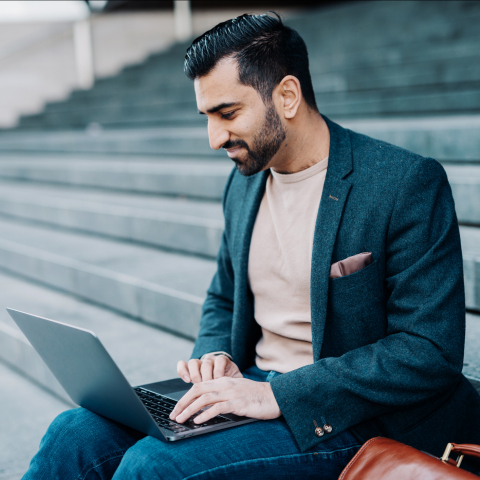 Man sitting on stairs and watching into his laptop